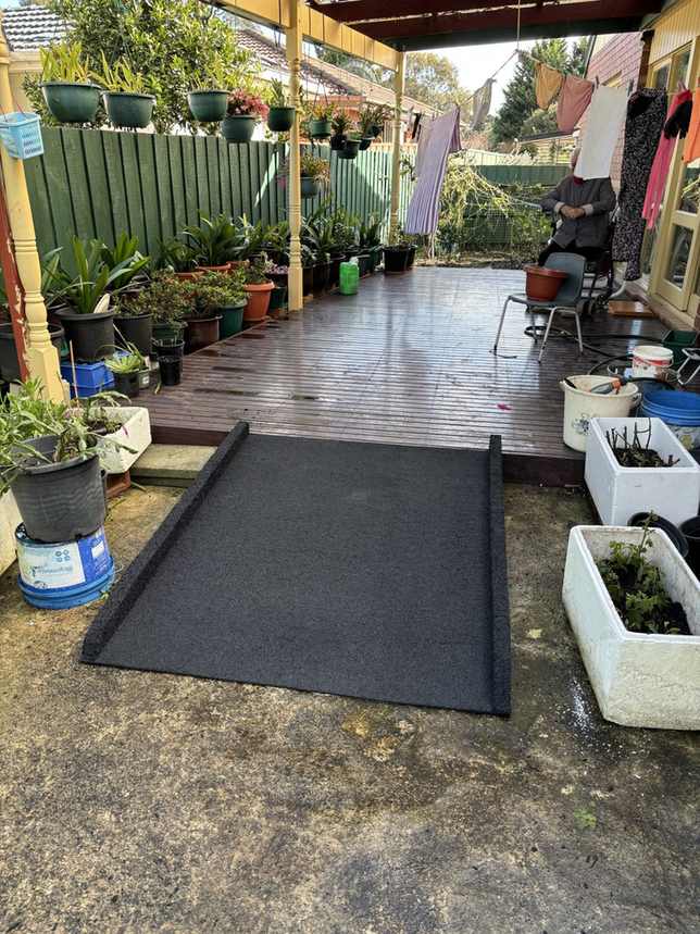 Backyard rubber wheelchair ramp Long rubber wheelchair ramp installed across a backyard patio