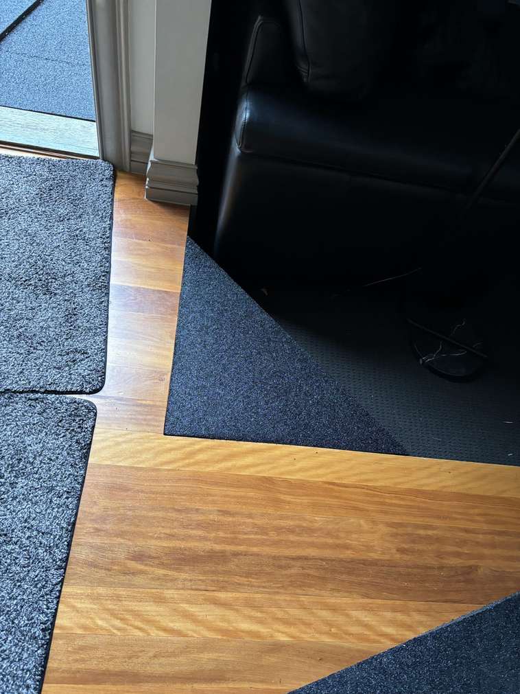 Carpet to timber transition ramp Rubber transition ramp between carpet and timber flooring beside a lounge