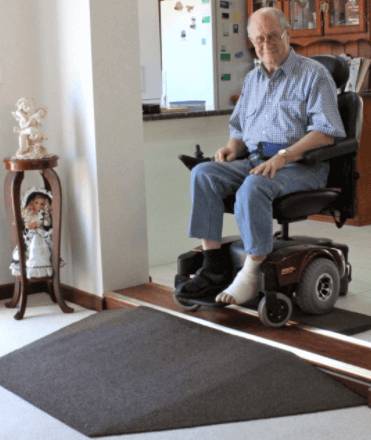 Rubber threshold ramp for power wheelchair access Elderly man in a power wheelchair crossing an indoor rubber threshold ramp