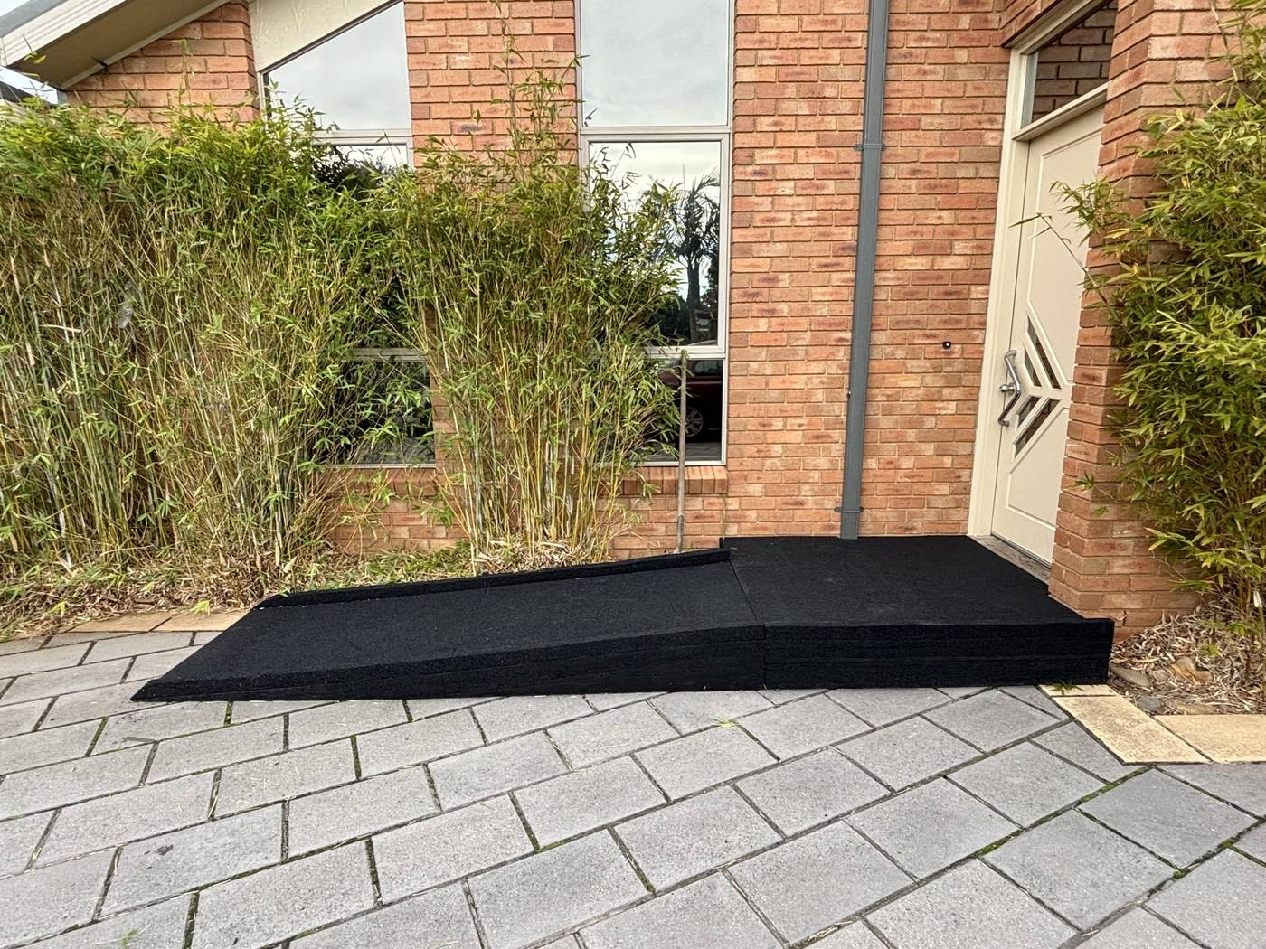 Front door rubber disability ramp Wide rubber disability ramp at the front door of a brick home with bamboo garden