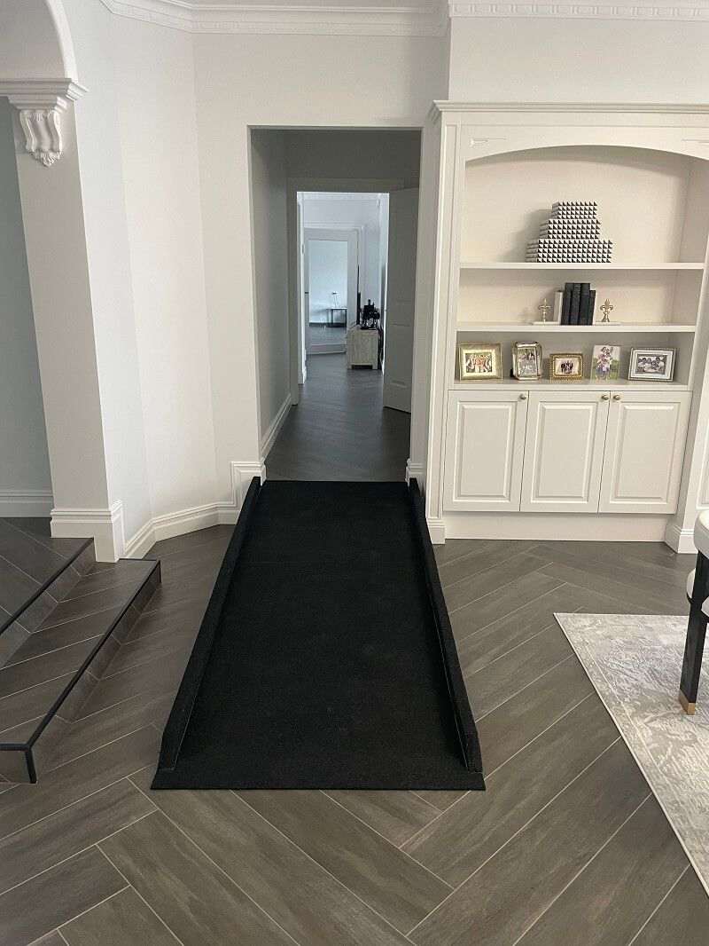 Indoor rubber disability ramp bridging a step between living areas and hallway