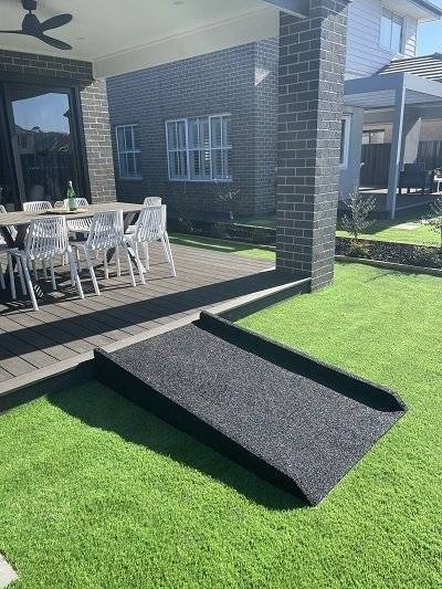 Outdoor rubber ramp from a timber deck down to an artificial lawn