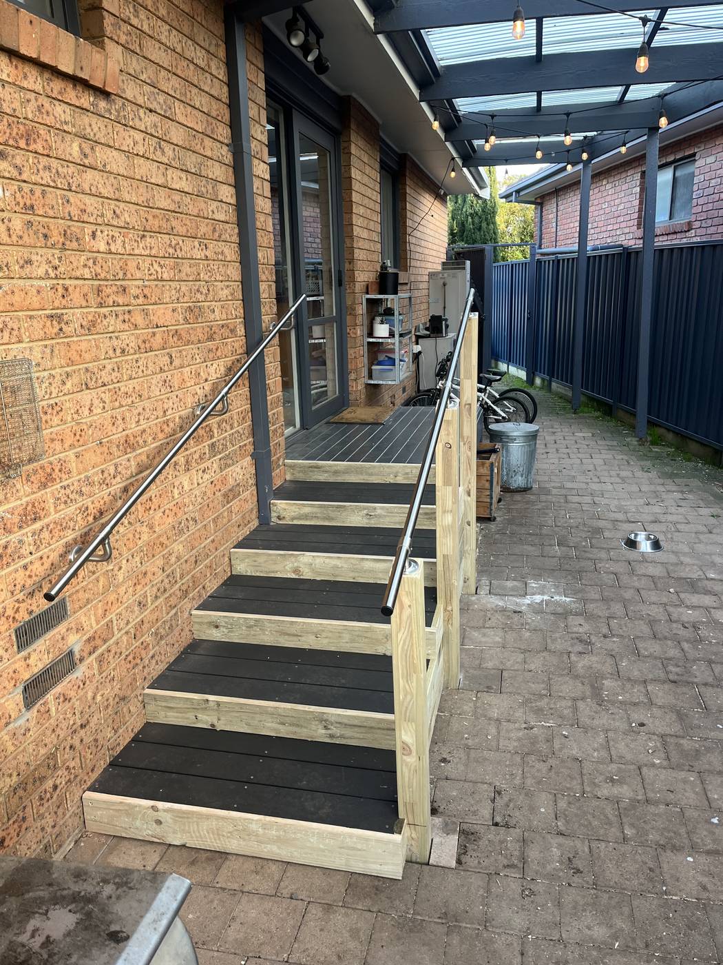 Platform steps with handrail Timber platform steps with rubber treads and a side handrail beside a brick home