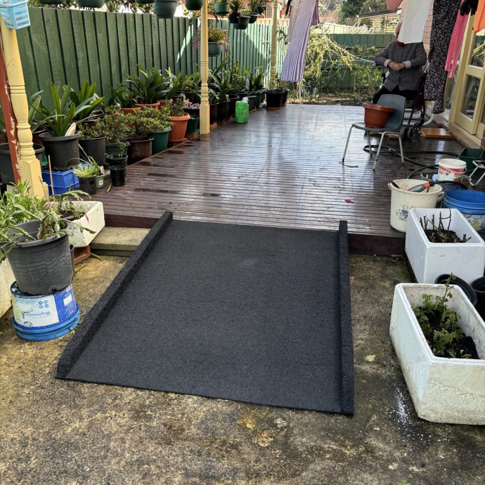 a patio with a black mat and potted plants